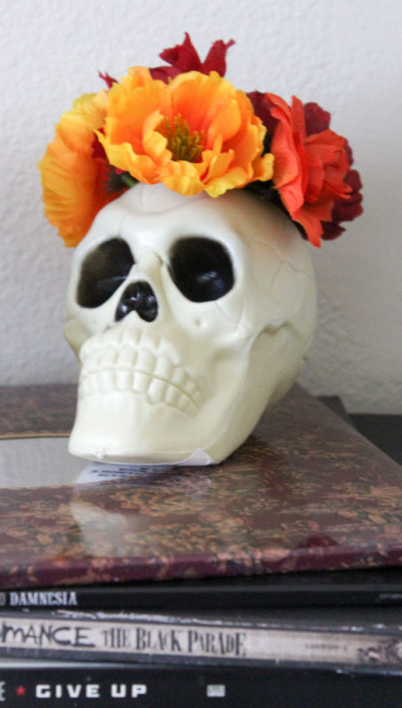 Make a DIY Skull Vase in under 5 minutes! Just cut a hole in the top of a plastic skull and fill with fake flowers!