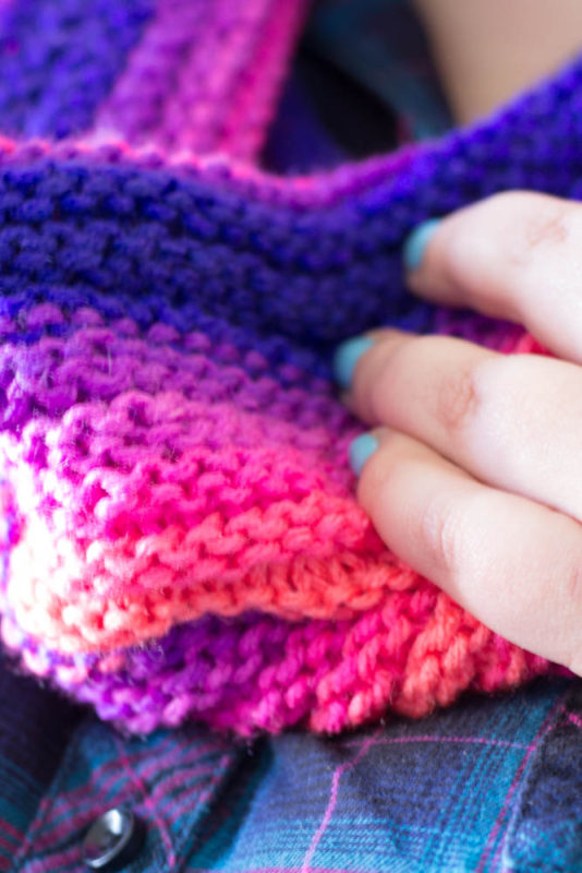 Knit with straight needles, this knit gradient cowl scarf is perfect for beginner knitters learning new stitches. Grab your favorite yarn and get knitting!